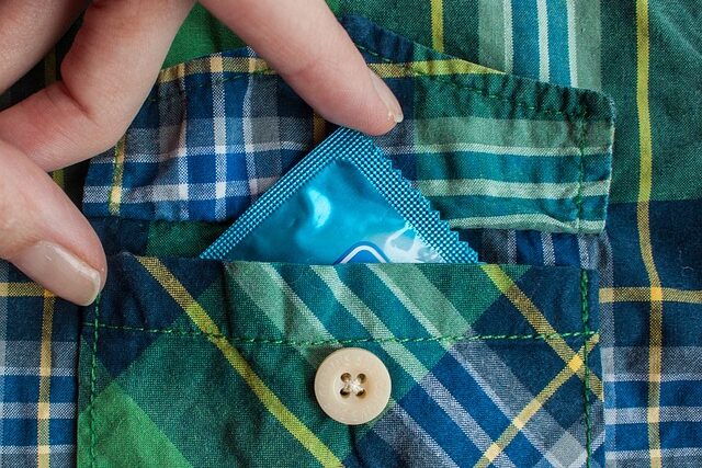 체크 셔츠 주머니에서 콘돔을 꺼내고 있다