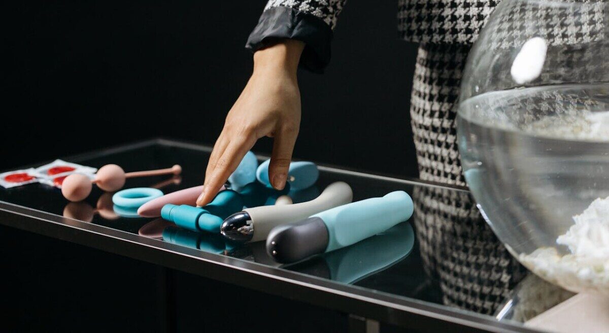 여러 딜도 중에 하나를 선택하기 위해 선을 뻗고 있는 여자