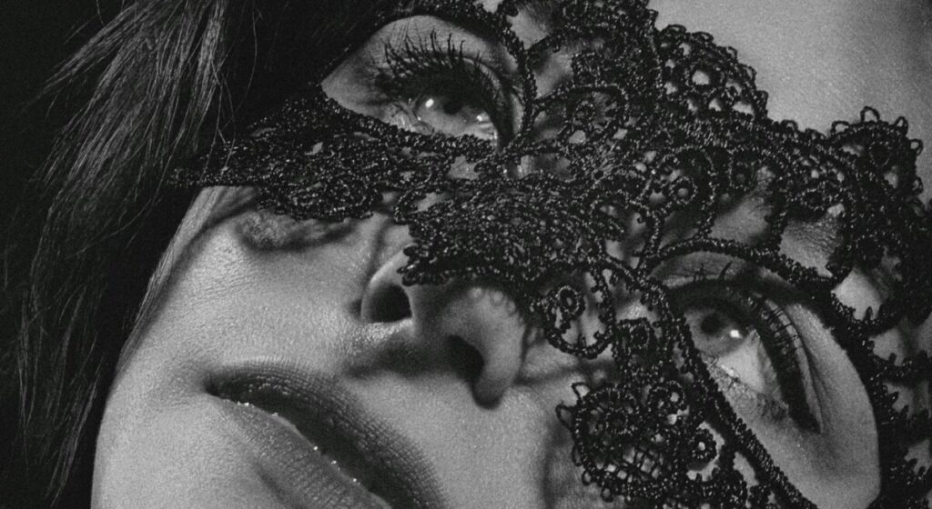 가면을 쓴 여성의 눈·코·입만 보이는 흑백 사진 — BDSM에서 익명성, 역할 놀이, 취향 존중을 강조하는 이미지