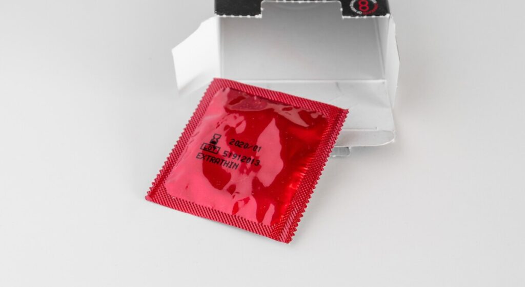 유통기한이 명시된 빨간색 콘돔 패키지를 통해 기간이 지난 제품 사용이라는 콘돔 실수를 점검하는 장면.