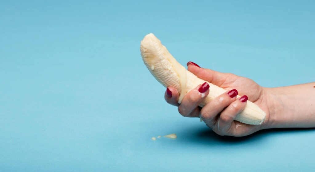 크림이 묻은 바나나를 손으로 쥔 모습, 쿠퍼액을 상징적으로 표현한 이미지