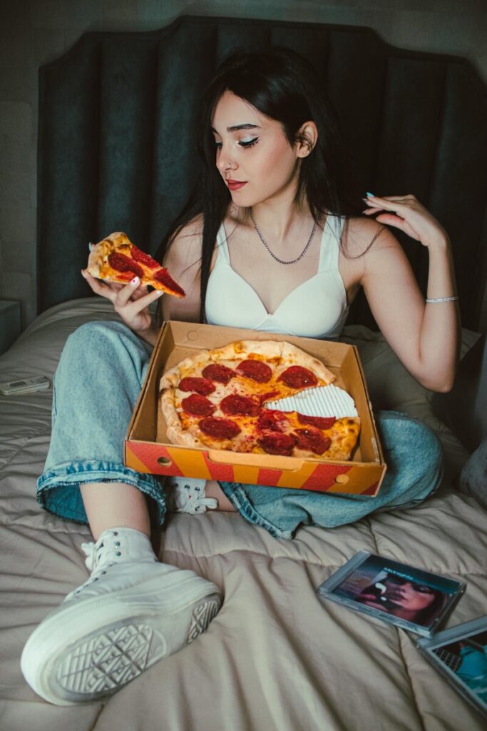 성광계 후, 속옷 차림으로 침대 위에서 피자를 먹고 있는 여성