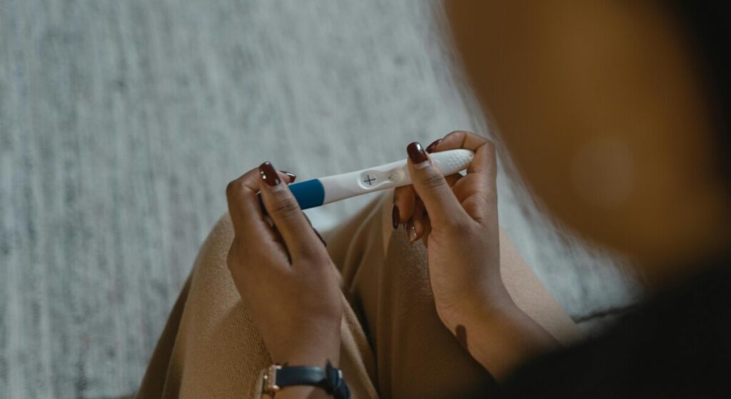 임신 테스트기를 들고 확인하는 손, 쿠퍼액 임신 가능성에 대한 실제적 고민을 나타낸 이미지