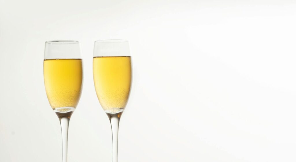 밝은 배경에 나란히 놓여 있는 두 개의 샴페인 잔. 두 명이 함께 즐기는 더블 딜도의 페어 플레이를 상징함.